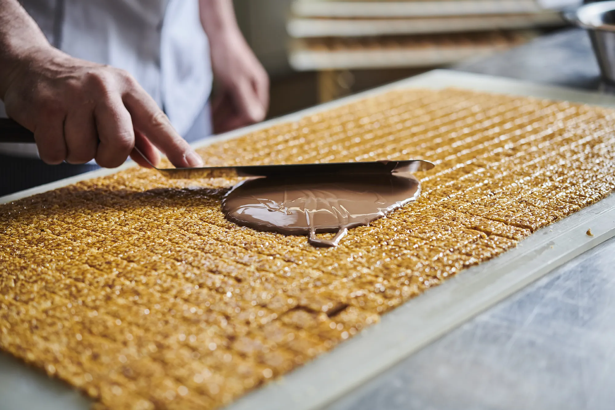 Nougat-Krokant, 6 St. Eine Person streicht Schokolade über Krokantblättchen