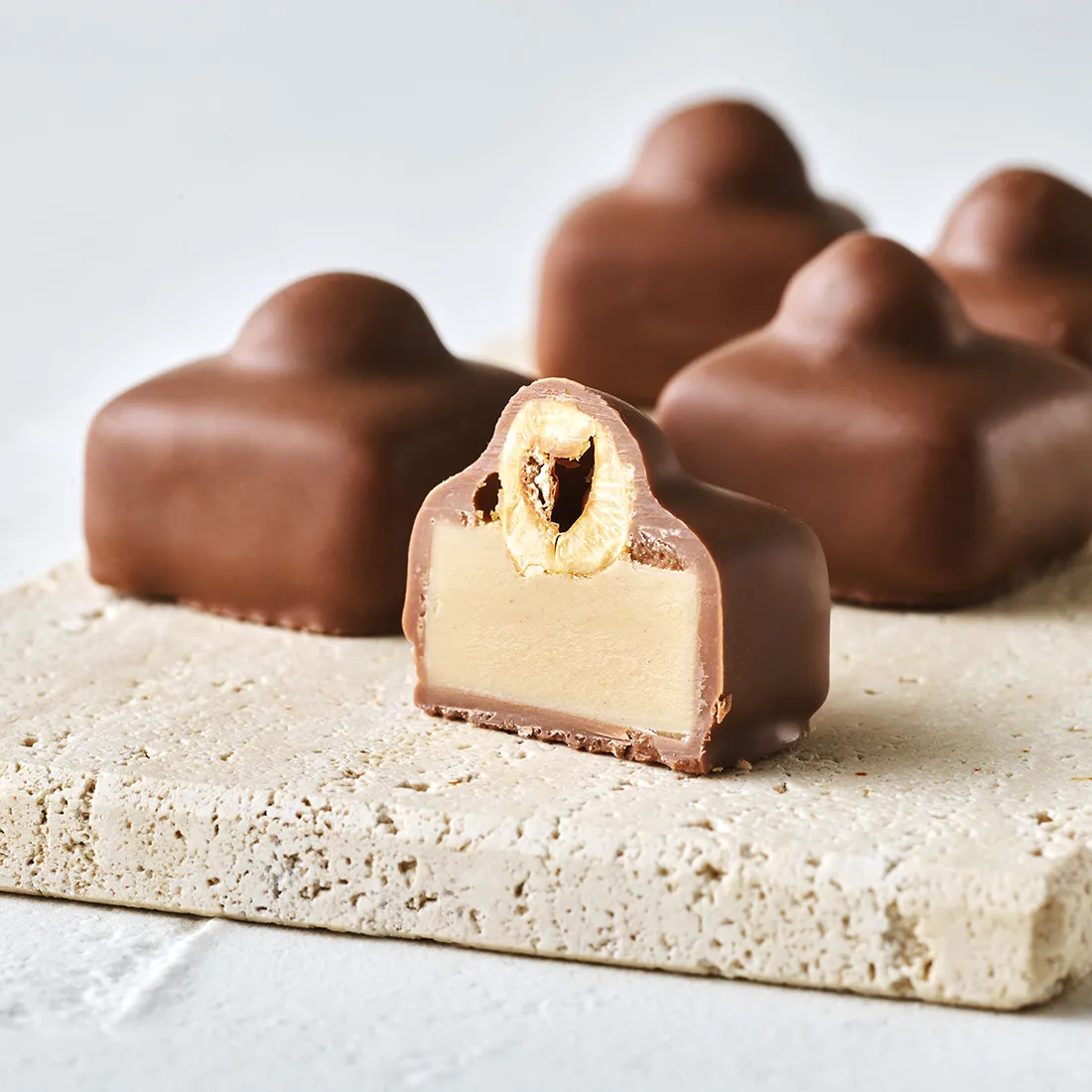 Stimmungsbild: Haselnuss-Nougat Praline mit Vollmilchschokolade überzogen dekorativ angeschnitten