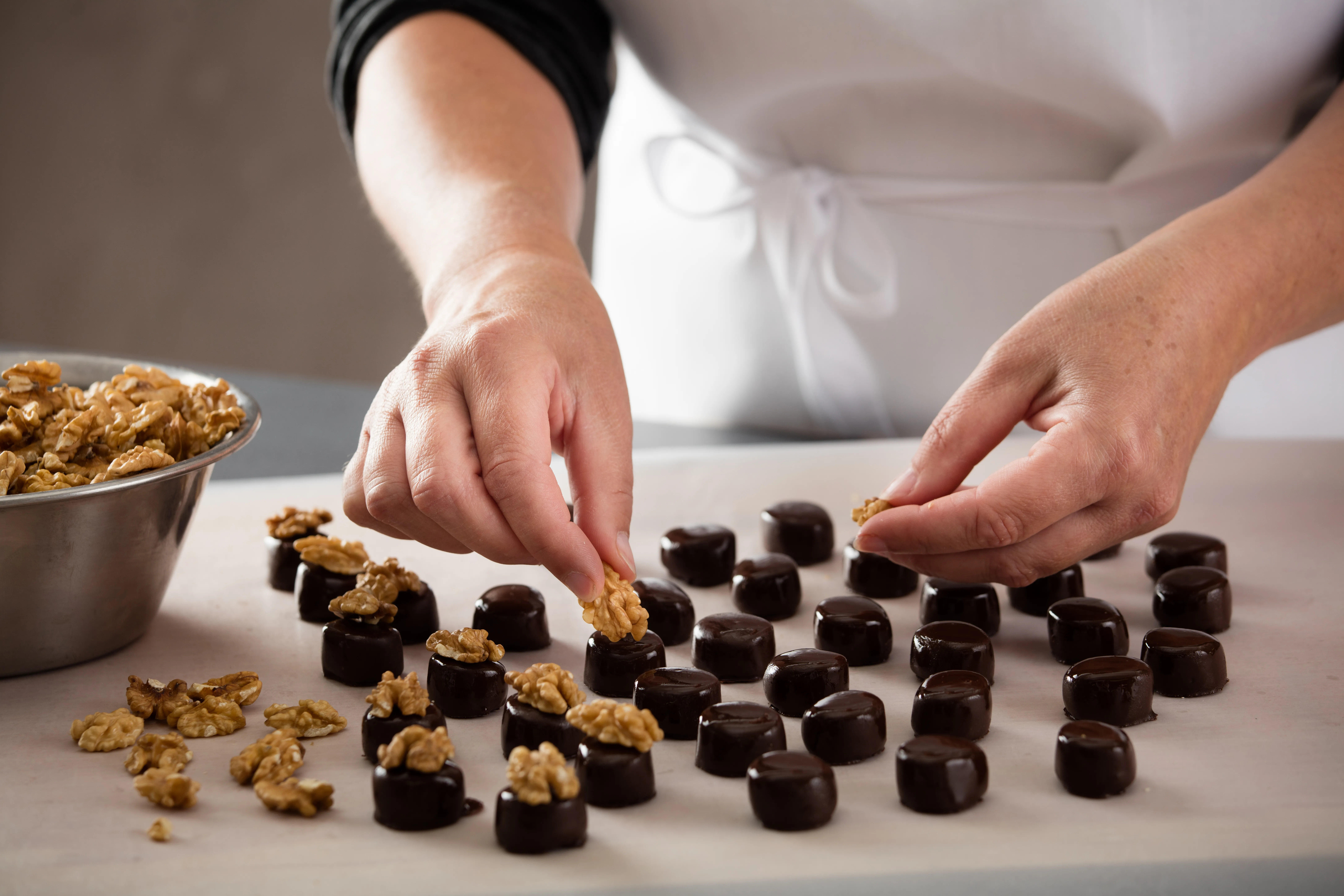 Eine Person legt einzelne Walnusshälften auf Marzipan-Pralinen